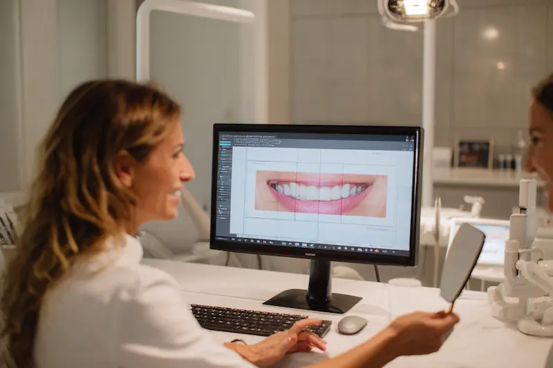 Odontóloga explicando diferencias entre blanqueamiento y carillas a paciente. Diferencias entre blanqueamiento dental y carillas estéticas